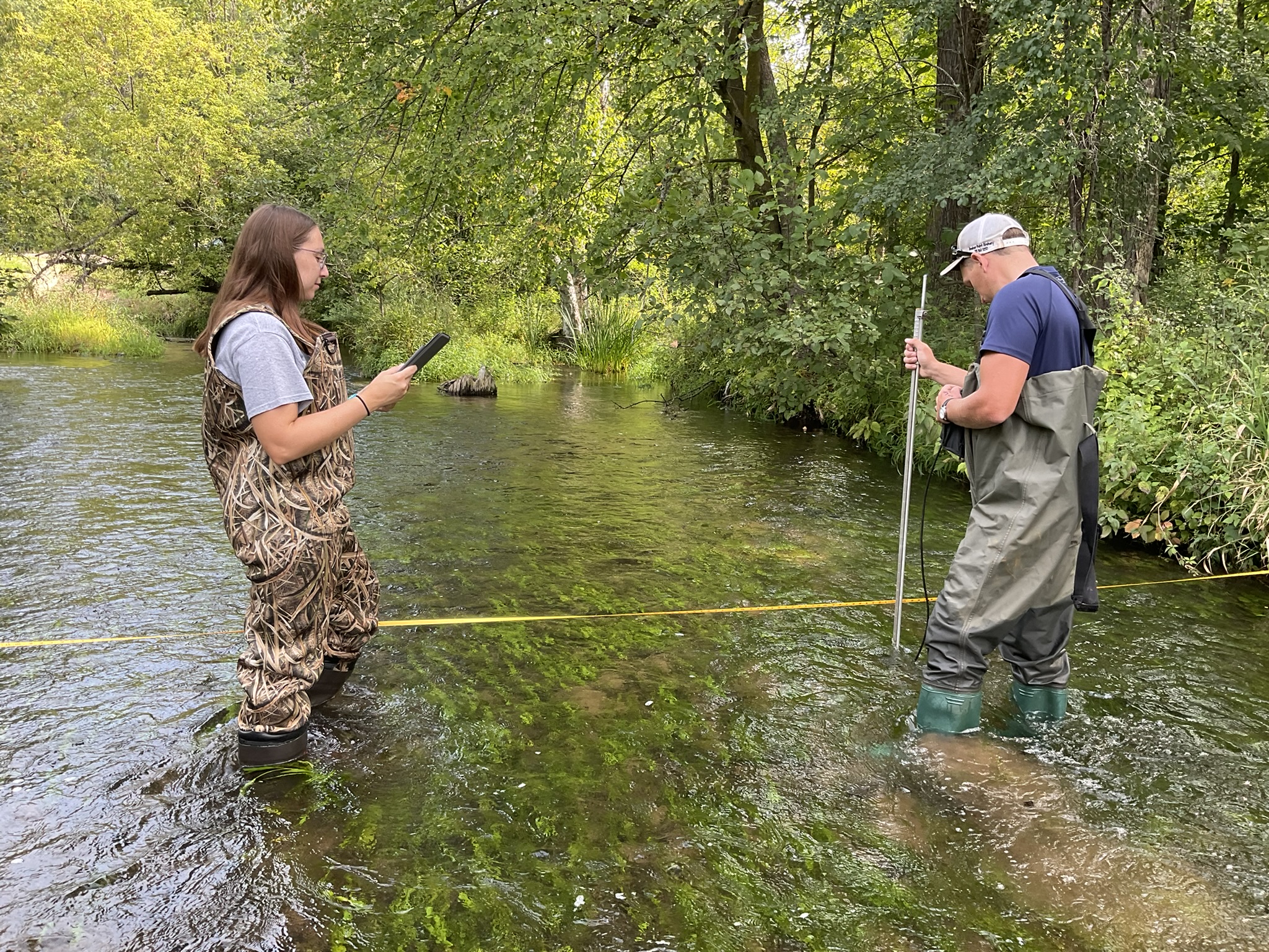 Hayley and Colton measure stream flow in a stream.