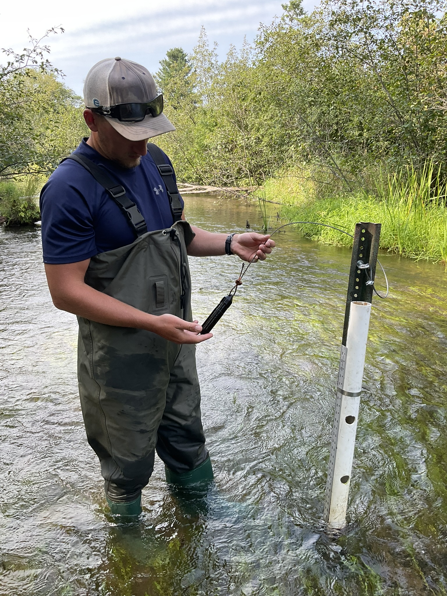 Colton holds a thermistor next to its post in the stream.