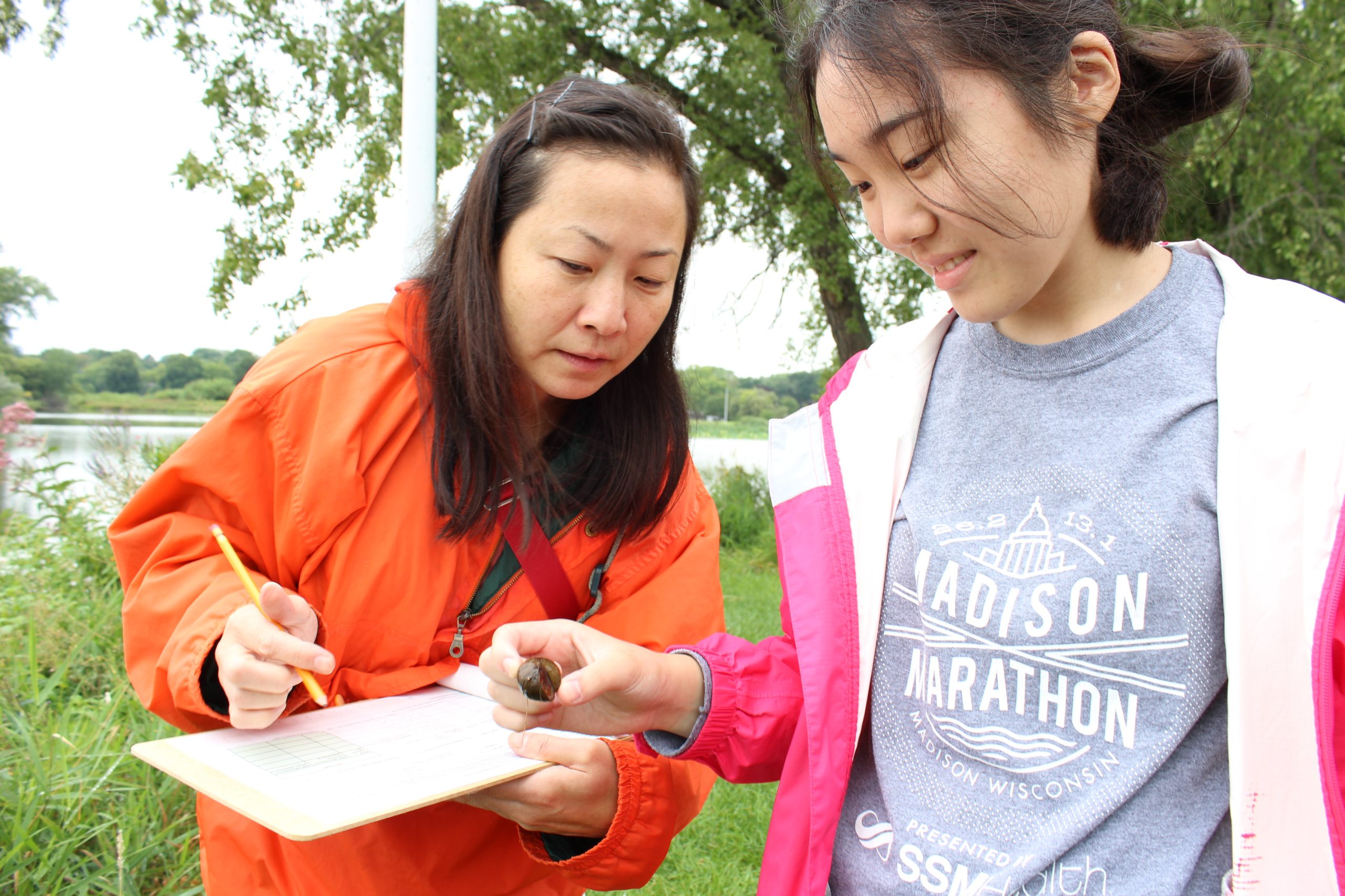 Two volunteers examining an aquatic invasive species. 