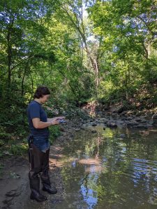 A person standing on the edge of a river writing down data