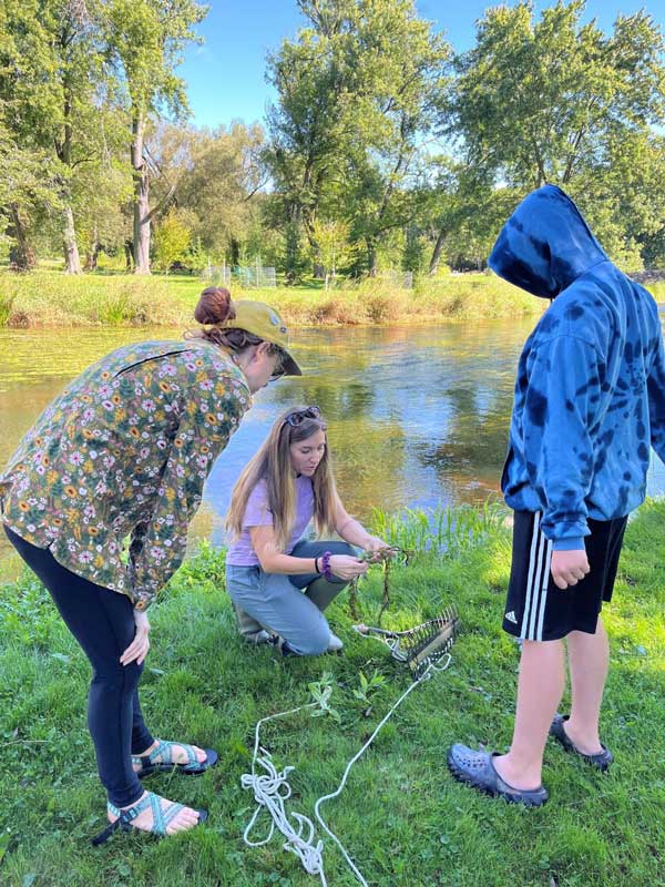 Two women watching and listening to a third women who is kneeling down to show them something