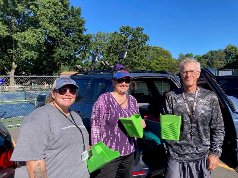A group of three people holding green scoop containers used for gathering samples