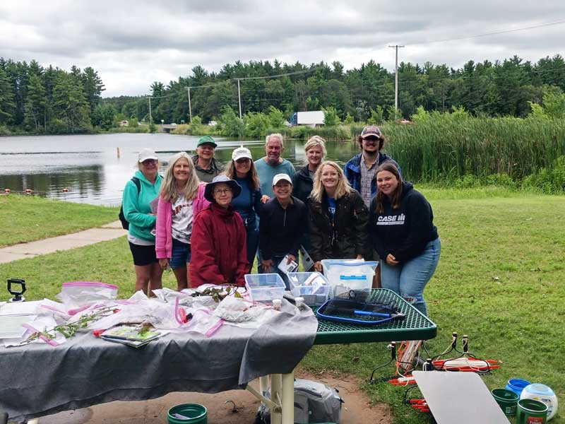 A group of volunteers posing in front of a table full of samples and supplies